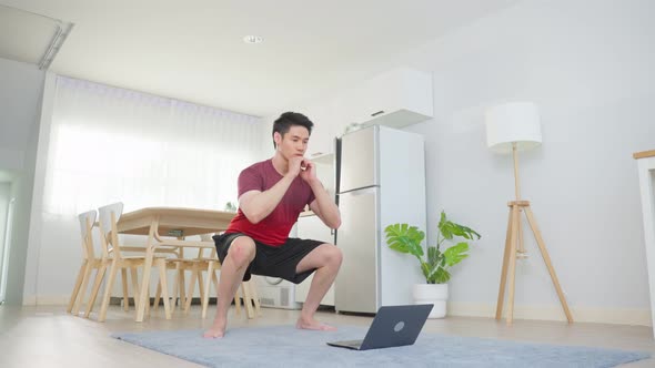 Asian young handsome man doing cardio exercise in living room at home.