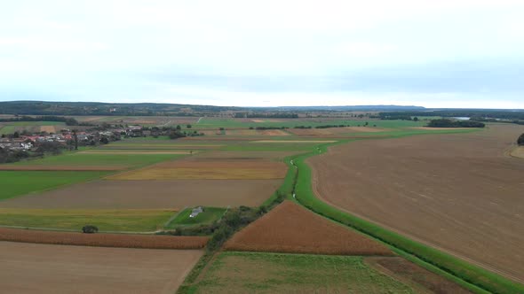 Flying over fields. Agriculture scene. Corn fields in Slovenia. Village nearby.