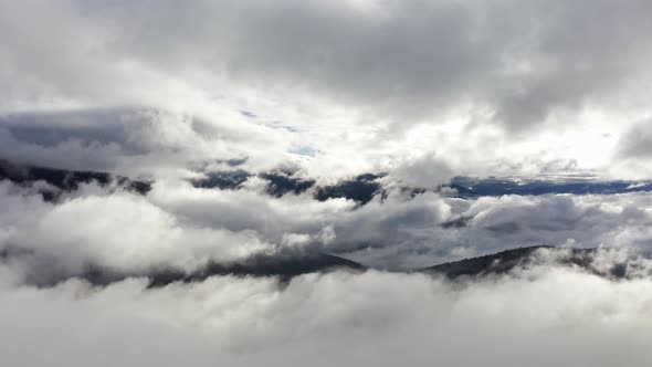 Flight Through Blue Sky with Clouds Over Mountain