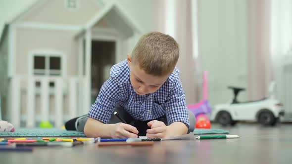 7-Years Old Boy Drawing with Felt Pen on a Floor
