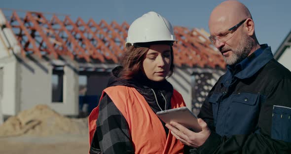 Concentrated Engineers Discussing Examining and Developing at Construction Site