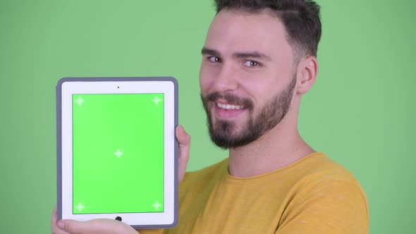 Face of Happy Young Handsome Bearded Man Showing Digital Tablet