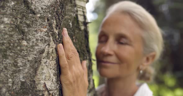 Portrait of Senior Gray Haired Woman Hugging Tree