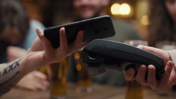 Unrecognizable man paying contactless in the pub. Shot with RED helium camera in 8K.