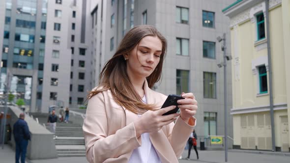 Portrait of Confident Business Woman Typing By Mobile Phone While Walking Outdoors at City Street