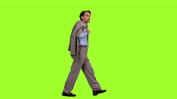 Businessman with Suit Jacket in Hand Walks on Green Background