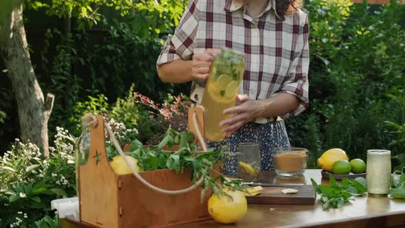 Woman Pouring Homemade Healthy Refreshing Summer Lemonade Into Glass Outdoors