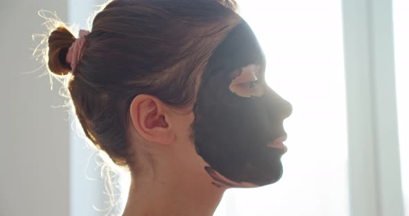Portrait of a Woman at Home in a Black Cosmetic Mask