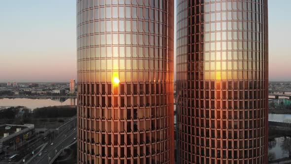 sliding aerial drone view of sunset reflecting on glass windows of twin skyscraper Zunda towers and