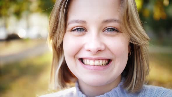 Beautiful smiling young woman looking at camera posing alone at outdoor. Happy girl student close up