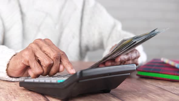 Senior Women Hand Using Calculator and Holding Us Dollar