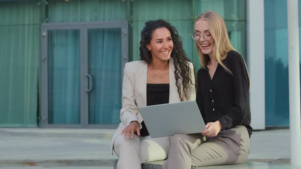 Happy Young Caucasian Businesswoman Using Laptop with Laughing Female Mentor Outdoors