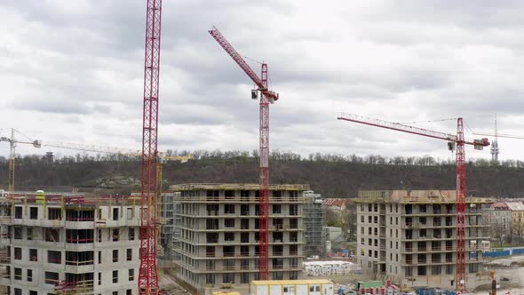 Red tower cranes working at construction site in Prague, cloudy day.