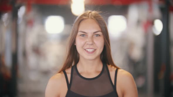 An Athlete Smiling Woman Drinking Water in the Gym