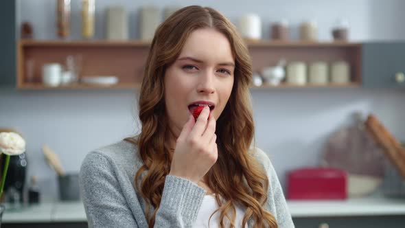 Beautiful Woman Eating Strawberry at Home Kitchen. Sexy Woman Tasting Berry