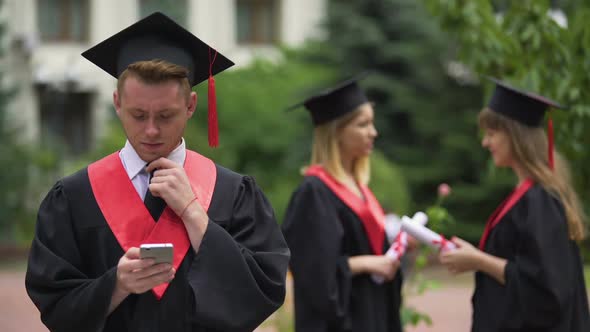 Handsome Graduate in Mantle Typing Messages on Smartphone, Checking Job Offers