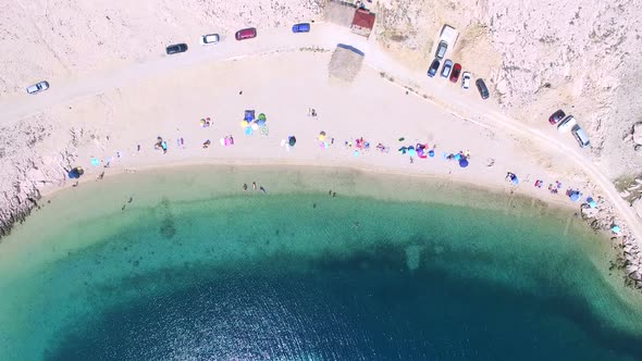 Flying above umbrellas and people on isolated beach of Pag island, Croatia