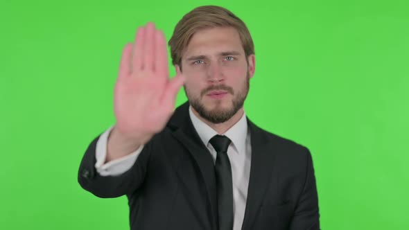 Rejecting Young Businessman with Stop Gesture on Green Background