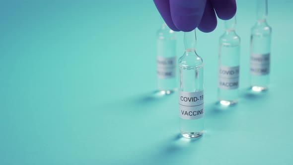 Coronavirus vaccine. A hand in protective medical gloves sets an ampoule among others in blur 