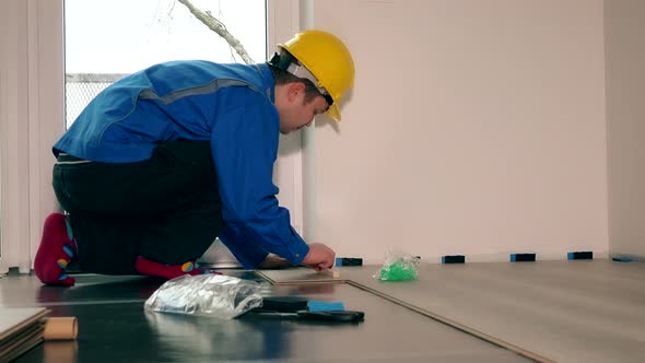 Professional Worker Man Laying Wooden Laminate Floor in New Apartment.