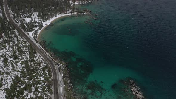 Aerial tilt shot revealing a road and the coastline of Lake Tahoe in Sierra Nevada, California