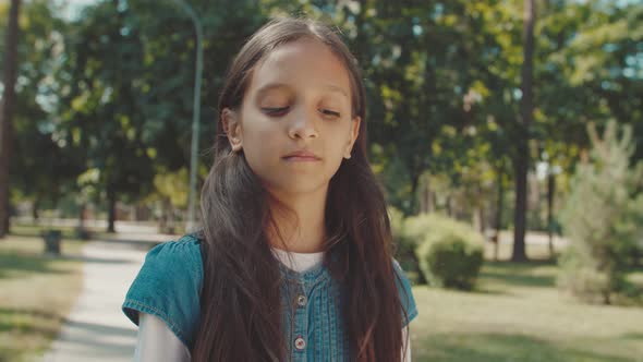 Portrait of Girl Looking Into Camera Expressing Sadness Outdoors