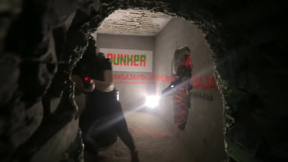 Group of happy teenagers with laser guns having fun on dark lasertag arena