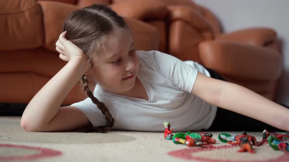 Girl with pretty face school age playing toy soldiers at home indoors. Close up shot