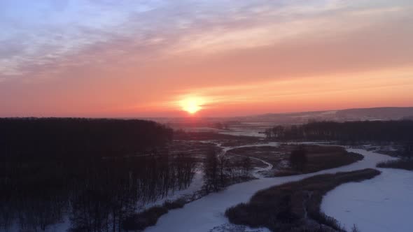 Pink Winter Frosty Evening  Bright Sun on the Horizon and Glare on the River Thaw