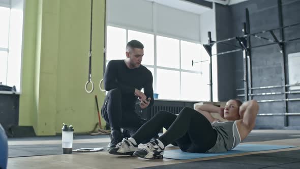Personal Coach Controlling Woman Doing Abs Crunches