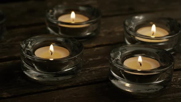 Tea candles with flaming wicks on a wooden background - CANDLES 005