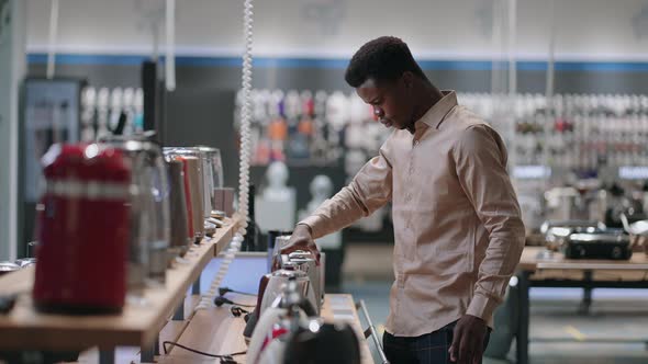 Black Guy is Shopping in Home Appliances Store in Mall Male Shopper is Viewing Electric Kettles