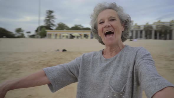 Senior Woman Holding Hands and Spinning Near the Sea