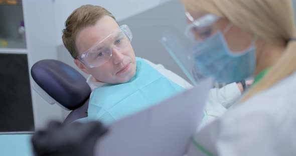 Doctor Orthodontist Consults a Young Man in a Dental Office