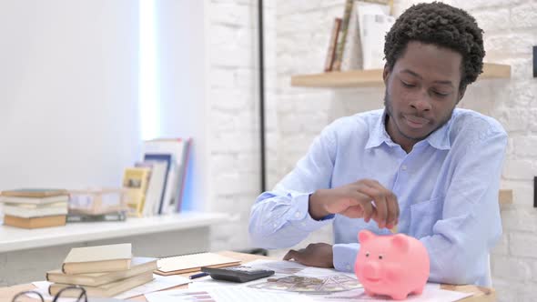 African Man Putting Money in Piggy Bank