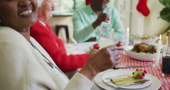 Happy african american senior woman celebrating meal with friends at christmas time