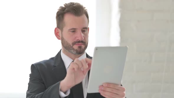 Attractive Young Businessman Using Tablet in Office