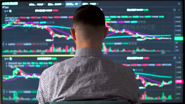 Professional Trader Analyzing Stock Market Data on Computer Scren and Taking Notes