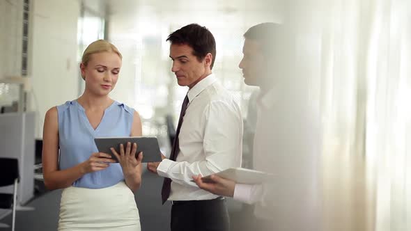 Businesswoman discussing project with male colleagues using digital tablet as reference