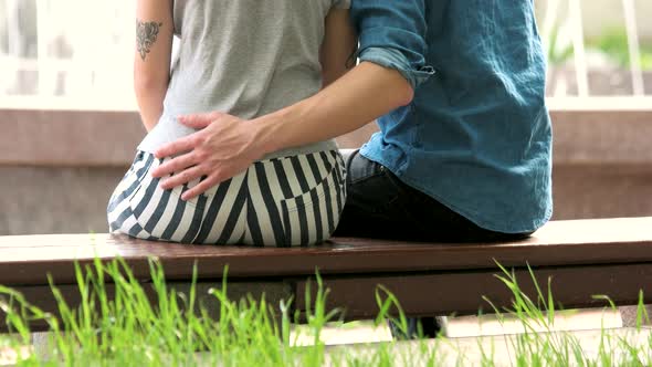 Young Couple Sitting on Bench Outdoors Back View