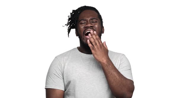 Portrait of Tired Dark Skinned Man Bearded and Mustached Yawning and Covering Mouth After Sleepless