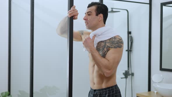 Refreshed Man Standing at Shower with White Towel on Shoulder Smiling