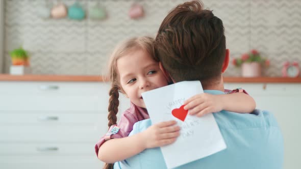 Little girl giving a card to dad for a holiday. The best gift for you