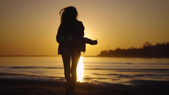 The Silhouette of a Beautiful and Slender Woman Against the Backdrop of the Sunset Sky