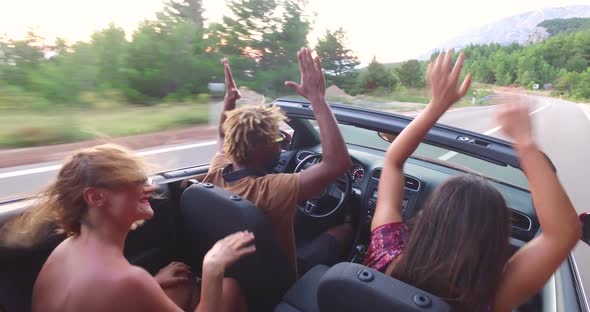 Young friends enjoying their road trip in convertible car
