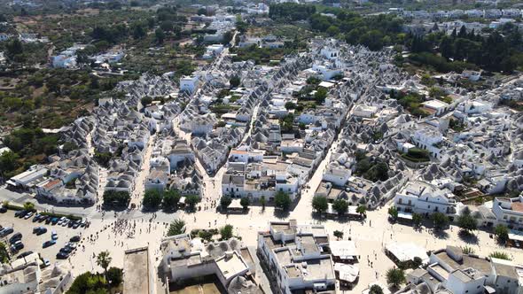 Aerial drone wide shot pushing to beautiful town Alberobello, Italy. whitewashed stone huts with con