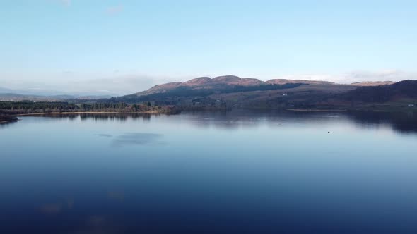 Lake with Ben Lomond mountain in background, Scotland. Aerial backward ascending