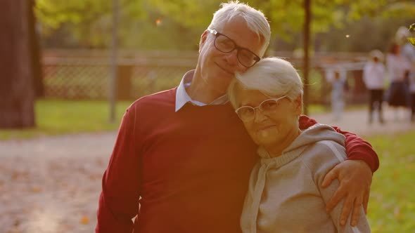 Portrait of Two Senior Grandparents Hugging and Smiling to the Camera