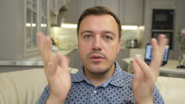 Young Adult Man Sitting on Sofa at Home and Looking at Camera Make Live Videochat