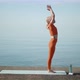 A Woman Reaches for the Sky Standing Against the Sea on a Yoga Mat - VideoHive Item for Sale